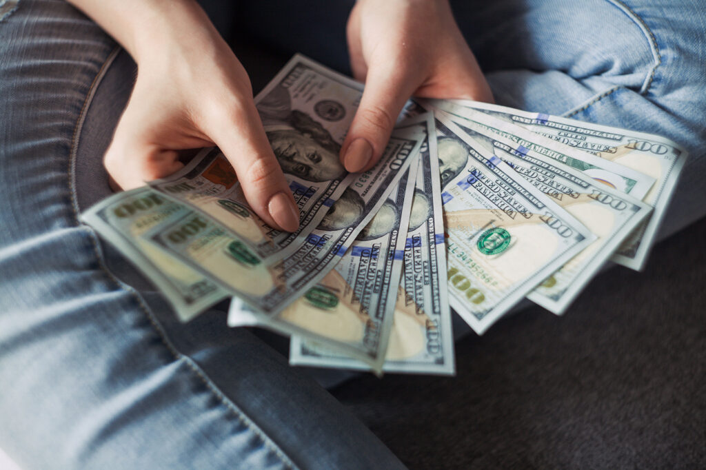 Person sitting down holding hundred dollar bills fanned out.

#CommercialRealEstateLoan